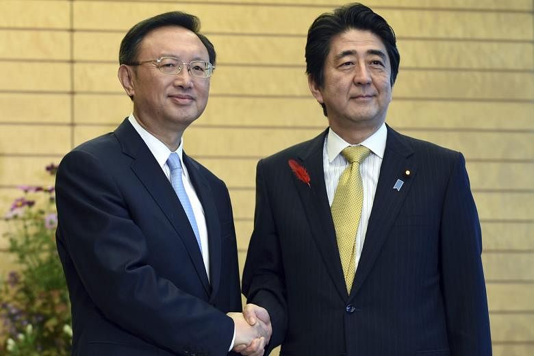 Chinese diplomat Yang Jiechi and Japanese Premier Shinzo Abe (right) had a "warm and friendly" meeting yesterday.