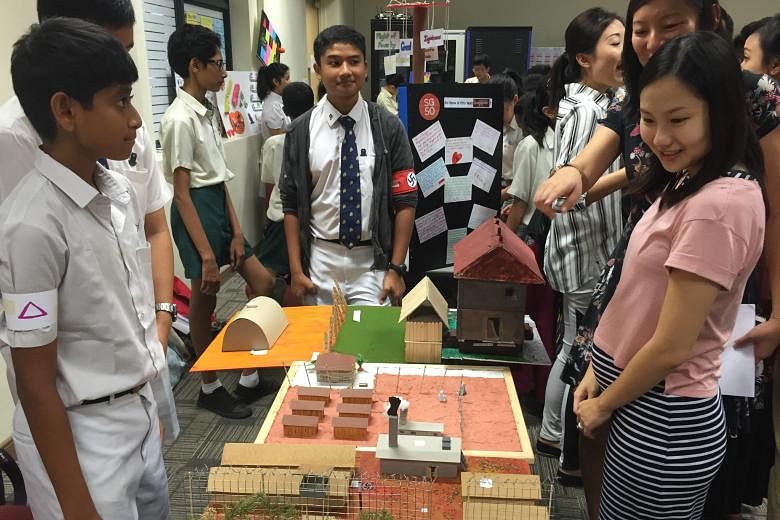 Secondary 2 students Mark Joshua John (in cardigan), Pranav Ghosh (far left) and Kenji Ng (partially hidden) showing visitors their model of the Auschwitz concentration camp at the recent National Schools Literature Festival.