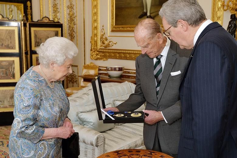 Britain's Prince Philip (centre) being presented an insignia of a Knight of the Order of Australia on April 22 by Queen Elizabeth (left) as Australian High Commissioner Alexander Downer looked on.