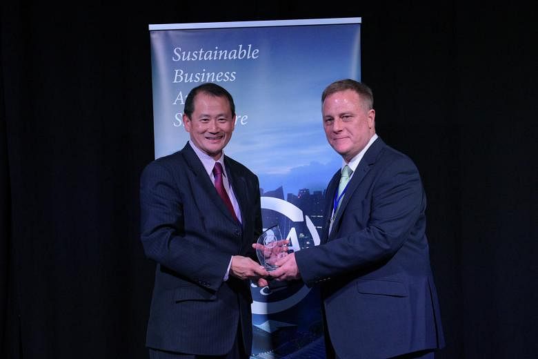 Mr Andrew Buay (at left), vice- president of group corporate social responsibility at Singtel, receiving the stakeholder engagement and materiality award from Mr Tony Gourlay, chief executive of Global Initiatives.