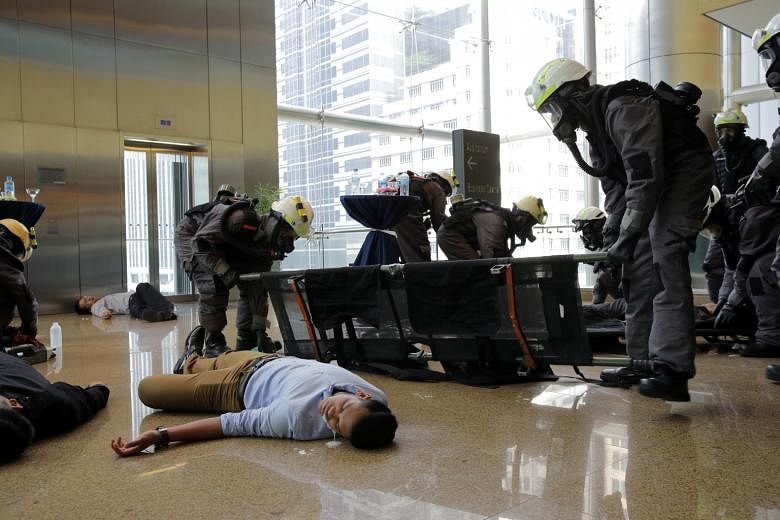 In the second simulated scenario at Esplanade Park, office workers were affected by the explosion. SCDF staff cutting open a victim's clothes for the decontamination process after a chemical agent attack. In the first simulation, office workers at On
