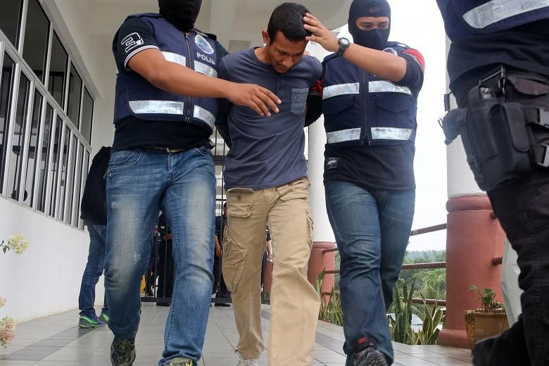 The Malaysian police have detained more than 100 suspected Malaysian militants, including former commando Muhammad Adibzakir Zahri (centre), who was charged in September with encouraging membership in ISIS.