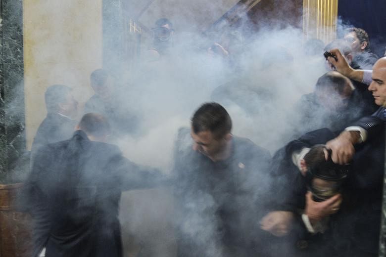 Members of Parliament leaving the chamber after tear gas was released by opposition lawmakers at Kosovo's Parliament in Pristina on Monday. It is the latest in a series of long-running protests against government agreements made with Serbia.