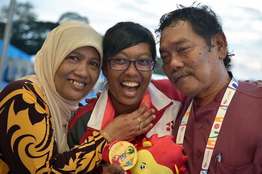 Syahidah Alim (sitting) celebrating her second archery gold medal yesterday. She won the women's individual compound event and partnered Robert Fuchs (left) to capture the mixed team title as well.