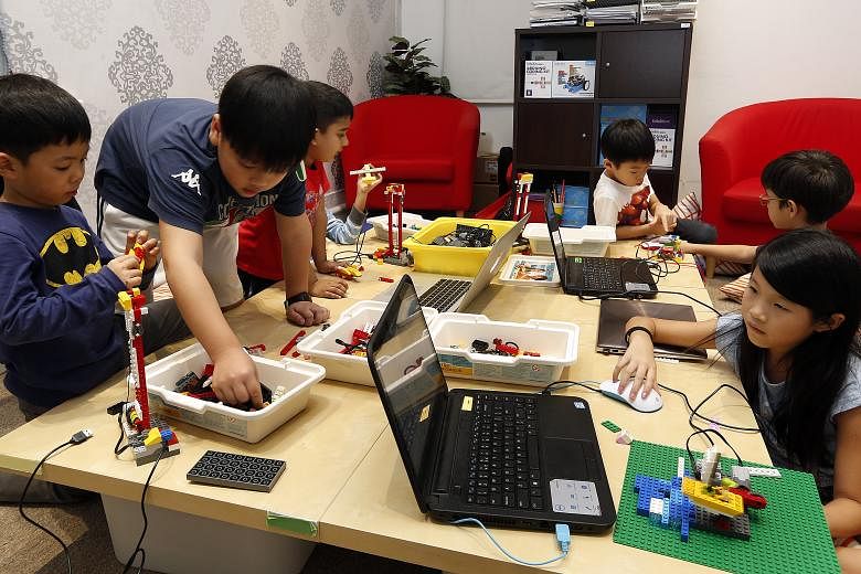 Five-year-old Christian Ong (far left) is interested in the mechanics of things. Here, he and fellow course mates learn how to program a robot launch pad using Lego pieces during a holiday workshop at In3Labs.