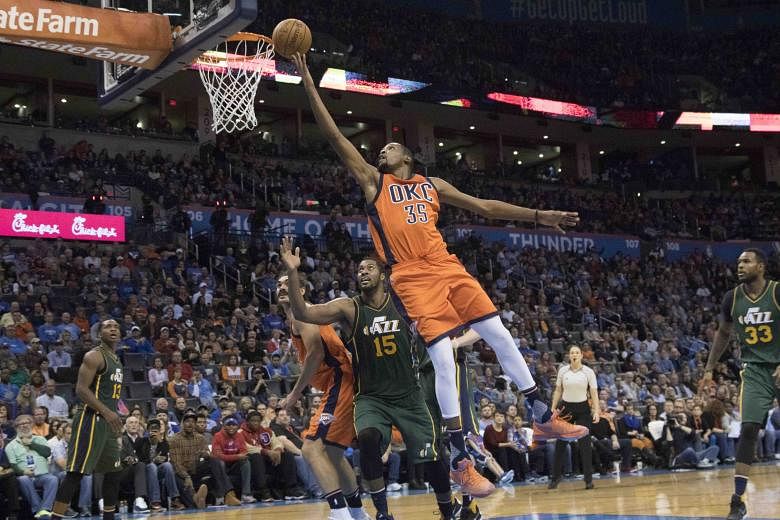 Oklahoma City Thunder's Kevin Durant (front) sailing past Utah Jazz's Derrick Favors for two points during the third period at the Chesapeake Energy Arena. The Thunder won 104-98 in overtime.