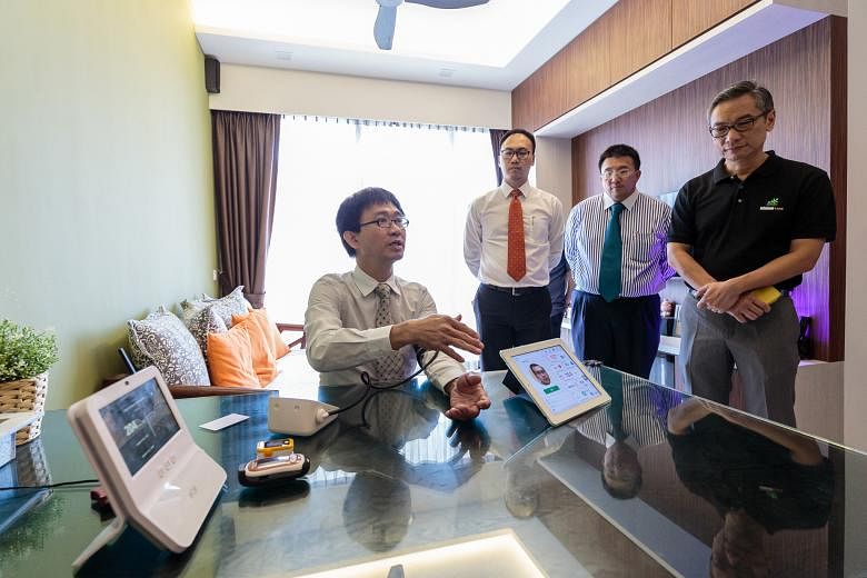 A Napier Healthcare representative (seated) shows (from right) Keppel Land property management general manager Lim Tow Fok and M1 chief product development and corporate solutions officer Willis Sim how the healthcare system used in the pilot program
