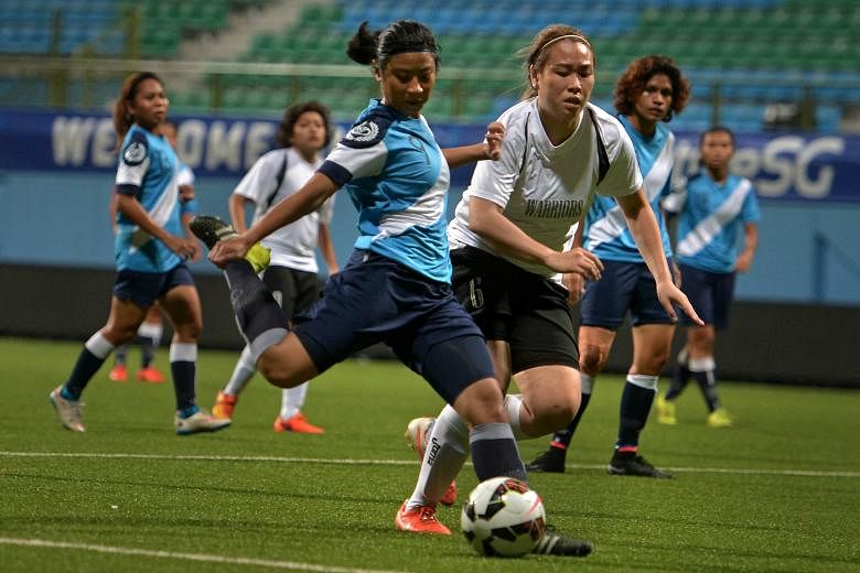 The Police Sports Association's Fatin Afiqah (left) attempting a shot against Warriors FC during their 2015 Women's Challenge Cup final at Jalan Besar Stadium yesterday. Police won 2-0 thanks to goals from Manami Fukuzawa (36th) and Fatin (44th). The