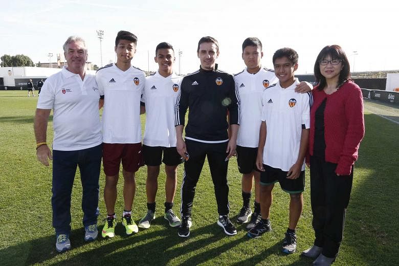 Young footballers from Singapore posing for photos with Valencia football club head coach Gary Neville (black shirt) and club chairman Chan Lay Hoon (right) last Friday. They are part of a 17-strong group of student-footballers - all of whom are unde