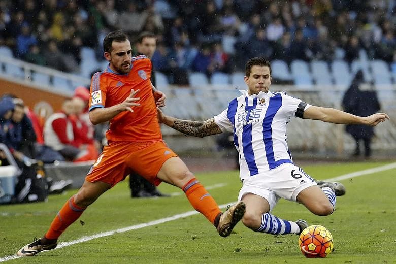 Valencia striker Paco Alcacer (left) fighting for the ball with Real Sociedad defender Inigo Martinez during their La Liga match. Gary Neville's side lost 0-2, leaving him still seeking a win in the league.