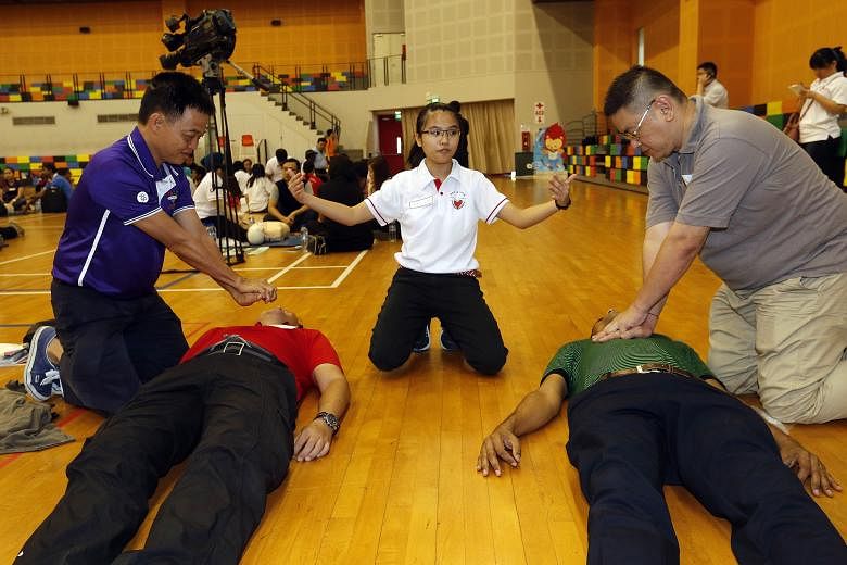MsTracy Koh (centre), 20, teaching Pasir Ris-Punggol GRC residents how to perform cardiopulmonary resuscitation at the launch of the Citizen First Responder course yesterday. Those who complete it will be certified as first aiders for two years.