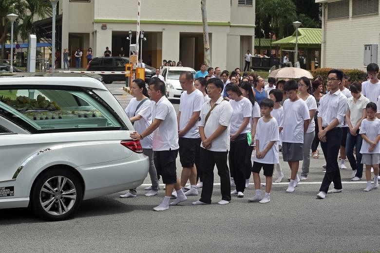 Mourners at the funeral procession for Madam Yep and her daughter, Kimberly, as their hearses leave for Mandai Crematorium yesterday.