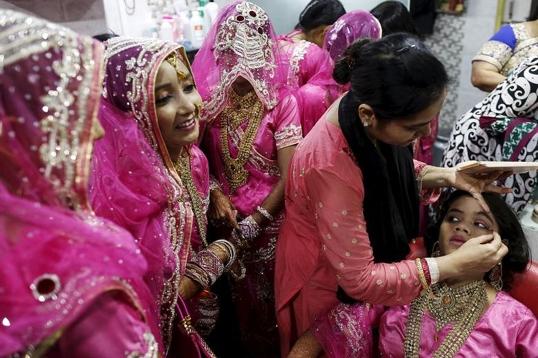 A Muslim bride getting her make-up done, as others wait, at a beauty parlour before the start of a mass marriage ceremony in Mumbai, India, on Wednesday. A total of 12 Indian Muslim couples took their wedding vows at the event organised by a Muslim v