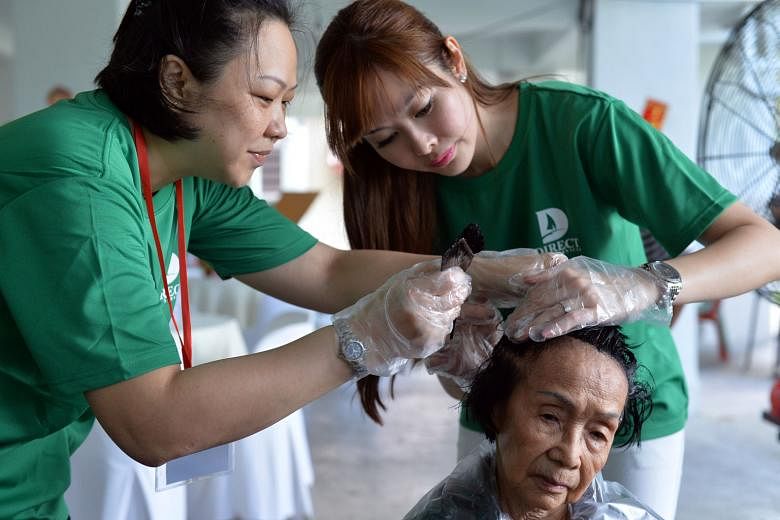 Ms Jenny Tay (right) and a volunteer dyeing the hair of Madam Florence Ho, 85, at the void deck of Block 4, Marsiling Road.