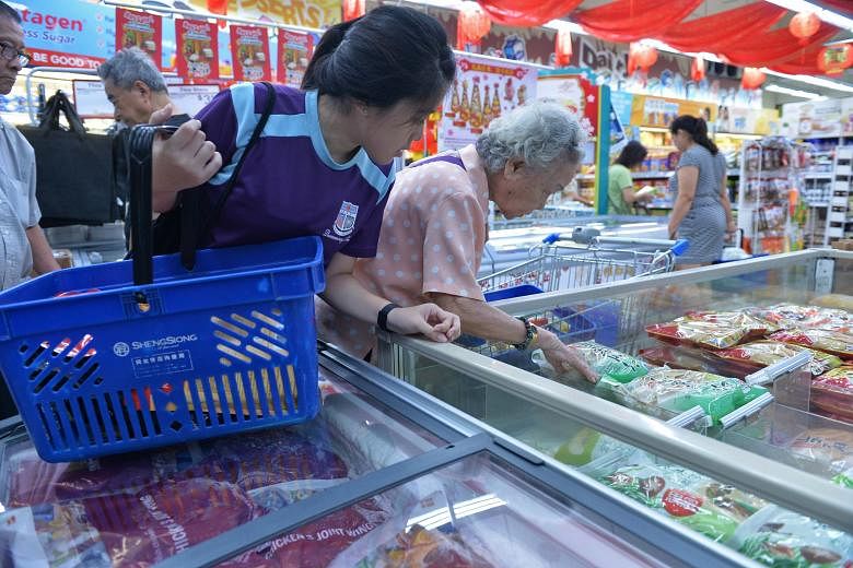 Queensway Secondary School student Ng Hui Yi, 16, helping Madam Poon Soo Lan, 88, with her grocery shopping. About 300 needy residents in Queenstown were treated to lunch and given a hongbao to buy groceries at an event yesterday. The red packet cont