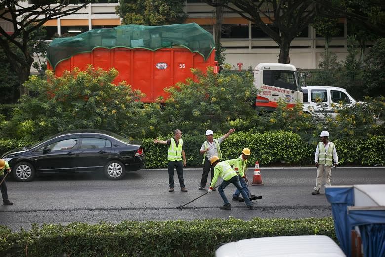 Workers resurfacing the affected section of PIE yesterday after the accident involving a tipper truck and an oil tanker caused the diesel spill. SCDF said it was alerted to the oil spill at around 1.40pm.