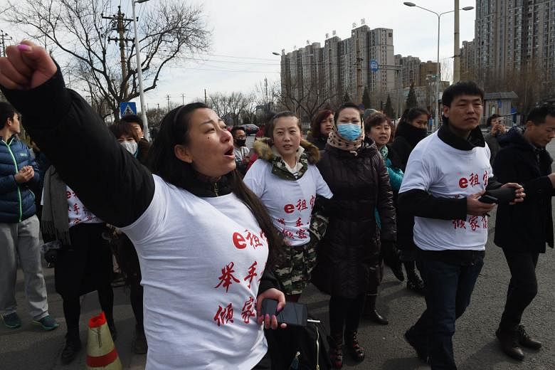 Investors wearing T-shirts that read "Ezubao: Raise hands, lose a family fortune" - a play on the company's slogan - protesting in Beijing yesterday against the P2P lender exposed as operators of a Ponzi scheme.