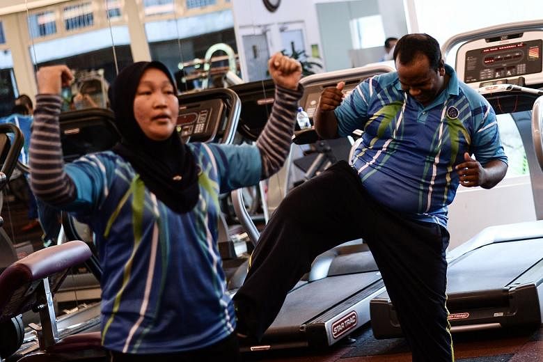 Malaysian police officer Suresh Mariah (right) exercising with others as part of the weight loss and fitness programme at the police headquarters in Kuala Lumpur. He is among thousands of officers who have been ordered to slim down.