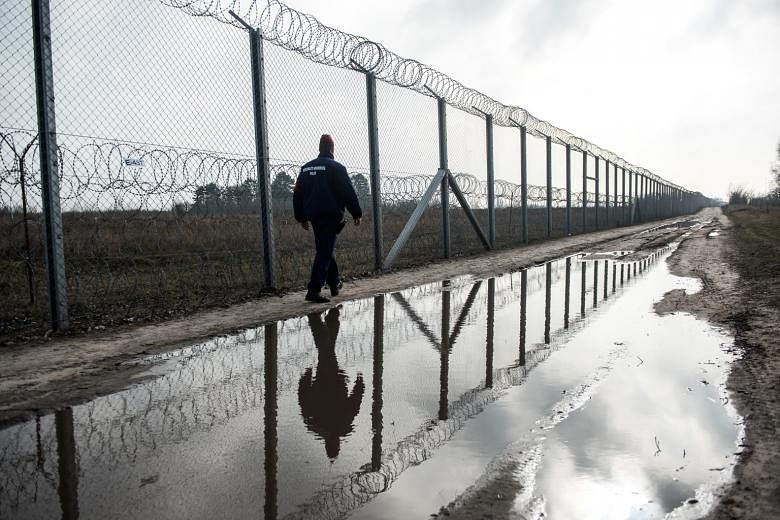 A member of the Hungarian police force on patrol along the razor wire-topped security fence on the Hungarian- Serbian border near Roszke, Hungary, on Wednesday. At the Brussels summit, Italian Premier Matteo Renzi warned eastern European leaders that