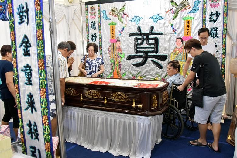 Mr Cheng Kiat Yan, Madam Tan Powi Kim's husband, in a wheelchair beside his wife's coffin at her wake in Tampines. Mr Cheng fractured his knee when he was thrown off his lorry in the accident.