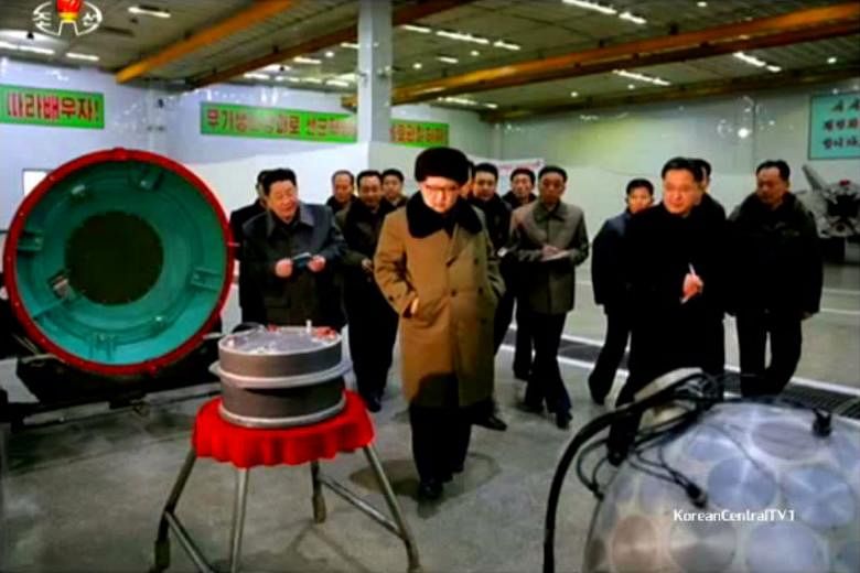 An image showing Mr Kim with parts said to be related to a warhead: a heat shield, a fuel-filled cylinder and a core sphere.
