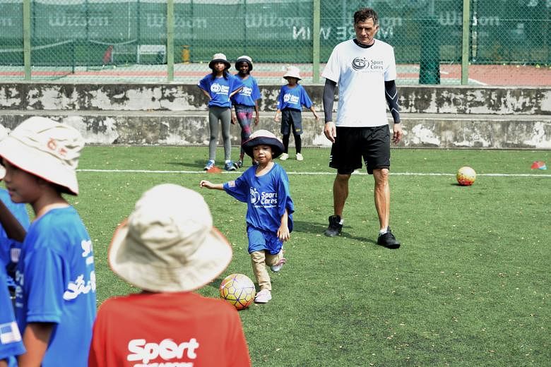 A young participant dribbling under the gaze of ActiveSG Football Academy principal and former national footballer Aleksandar Duric at a football clinic held at St Wilfred Field yesterday. The clinic, which was held by local community group SportCare
