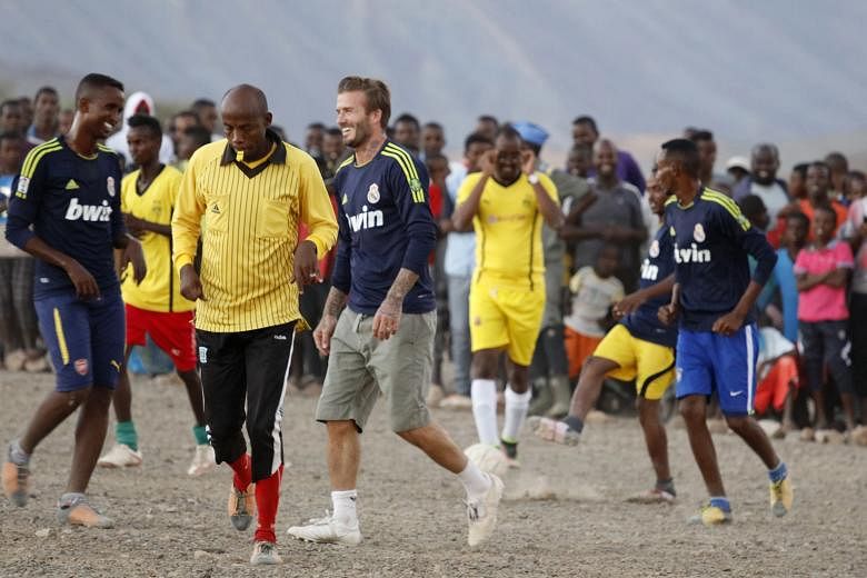 After playing football with students in Nepal, his face is covered with crimson paint, the national colour of Nepal. David Beckham poses with the children in Kumnga village (above) after an impromptu football match in the rain in Papua New Guinea, an