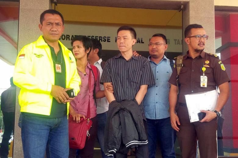Lim (in black striped shirt) being escorted to Jakarta where he was handed over to a US Marshal yesterday.