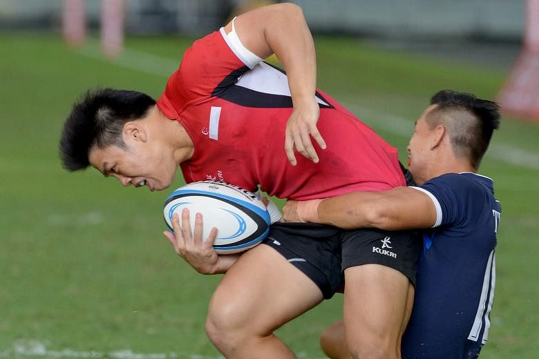 Singapore centre Nicholas Yau - who scored the home team's only try - is tackled during the 19-5 defeat by Thailand in the final of the South-east Asia Sevens at the National Stadium yesterday.