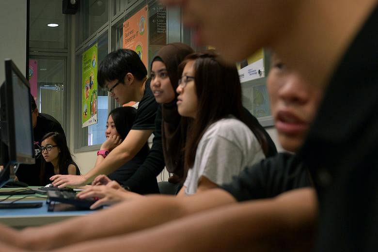 Students from Nanyang Polytechnic's School of Information Technology helping visitors attending the polytechnic's open house to play a cyber security game that they developed.