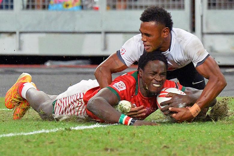 Left: It's wefie time for the victorious Kenyans, holding the trophy and wearing their gold medals. Below: Nelson Oyoo shaking off the challenge of Fiji's Amenoni Nasilasila to score Kenya's fifth try in their 30-7 pummelling of the series leaders in