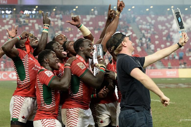 Left: It's wefie time for the victorious Kenyans, holding the trophy and wearing their gold medals. Below: Nelson Oyoo shaking off the challenge of Fiji's Amenoni Nasilasila to score Kenya's fifth try in their 30-7 pummelling of the series leaders in