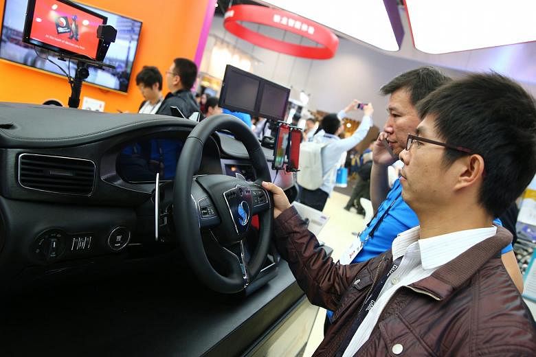A visitor tries out the Connected Car Solutions System at the Qualcomm exhibition booth at the 2016 Global Mobile Internet Conference in Beijing this month.