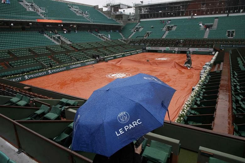 A sole umbrella-wielding spectator waiting in hope while the covers remain on the surface of the main Philippe Chatrier Court yesterday. The organisers of the French Open plan to introduce a roof to the main court, but that will not happen until 2020