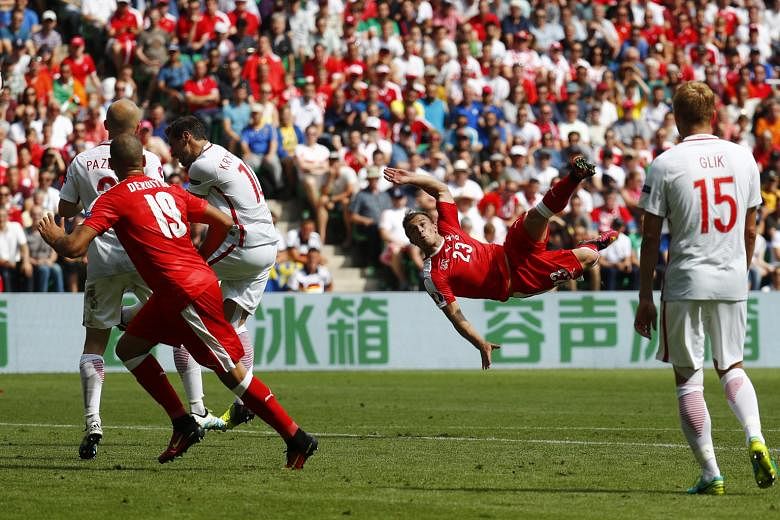 Switzerland's Xherdan Shaqiri (right) scoring a spectacular overhead kick in their Euro 2016 last-16 tie against Poland yesterday. His 82nd-minute goal cancelled out Jakub Blaszczykowski's 39th-minute opener, and the tie went into extra time and then