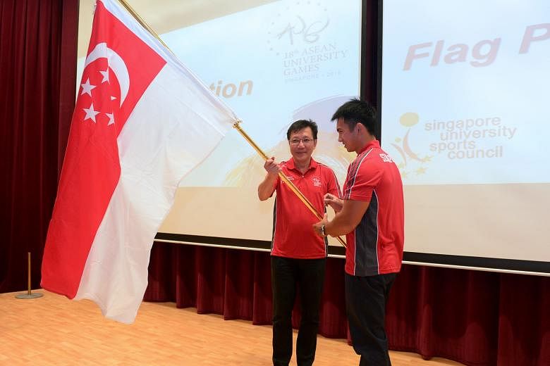 Associate Professor Tan Teck Koon (left), head of the Singapore delegation for the Asean University Games, presenting the Republic's flag to canoeist Mervyn Toh at University Town, the National University of Singapore, yesterday. The Singapore contin