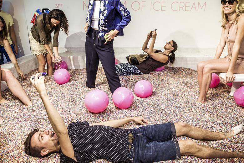 Visitors play at the Museum of Ice Cream's main attraction - a room with a swimming pool full of rainbow "sprinkles".