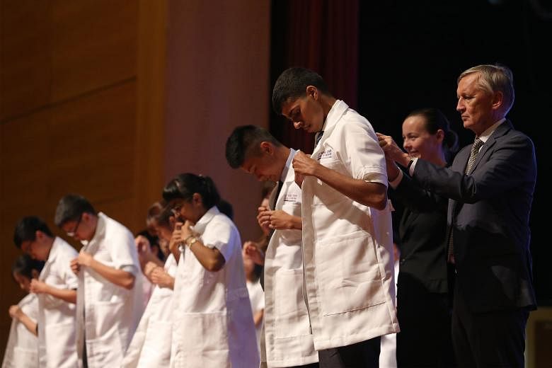 NTU medical students receiving white coats in a special ceremony yesterday. The coats symbolise the knowledge and compassion that they must exercise in the future.