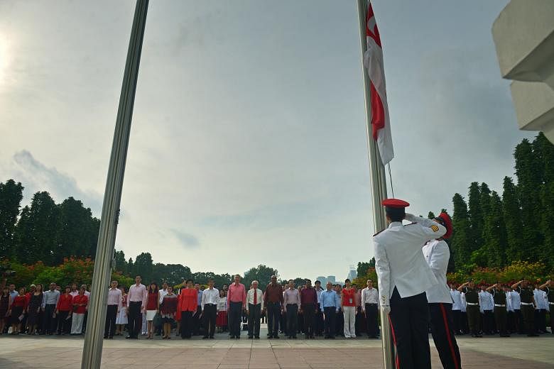 Presidential guards preparing for the flag-raising ceremony as staff from the Prime Minister's Office and President's Office gathered for the National Day observance ceremony held at the Istana yesterday. Attendees - including President Tony Tan Keng