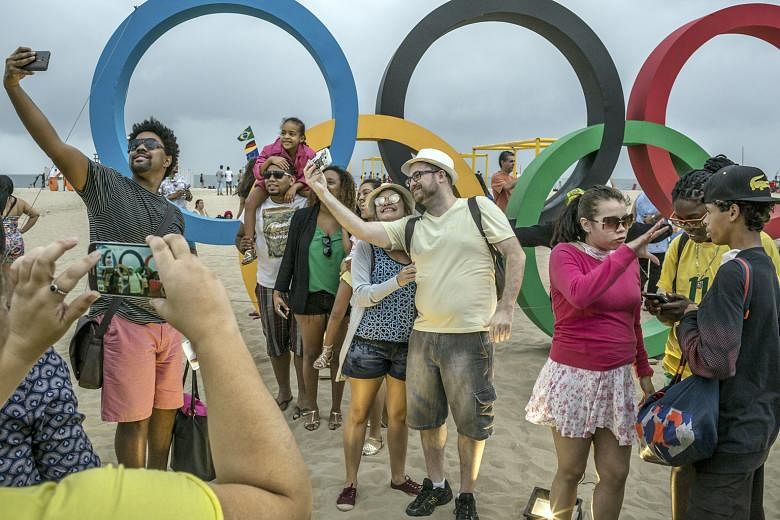 A Brazilian man uses his street cart rigged with a TV to watch the basketball match between Serbia and Australia. Locals and tourists stop by the Olympic rings next to the beach volleyball arena at Copacabana Beach to take photographs. At this arena,