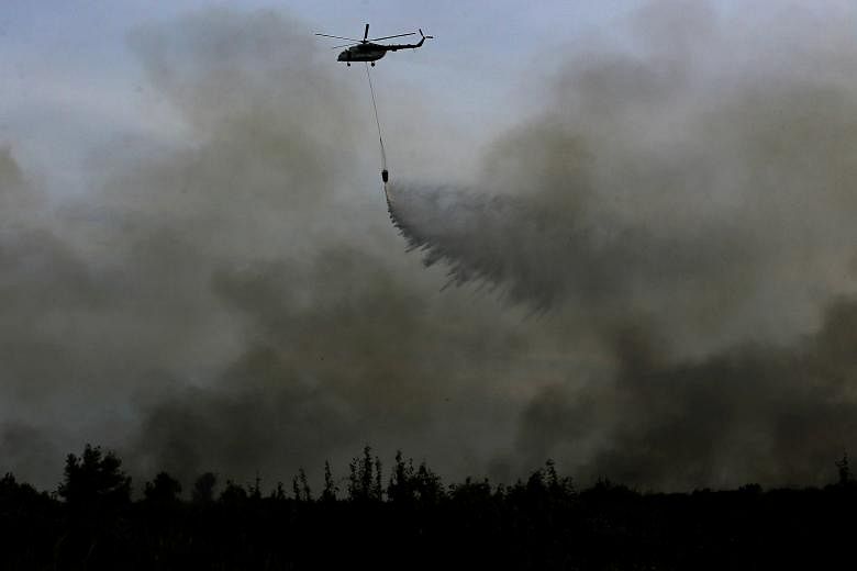 A helicopter dropping water on a fire in Ogan Ilir, near Palembang in South Sumatra, on Aug 11.