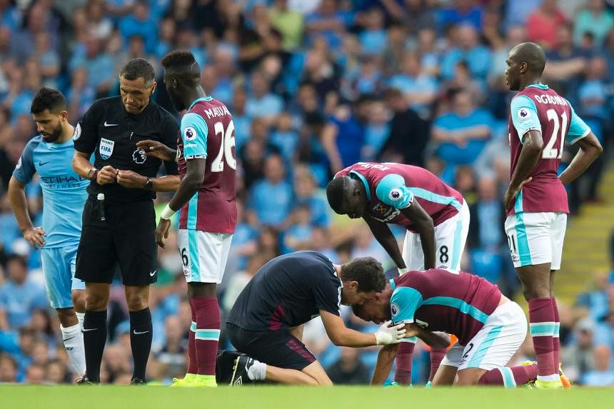 West Ham's Winston Reid (on ground) receiving treatment from a physiotherapist after a clash with Aguero.