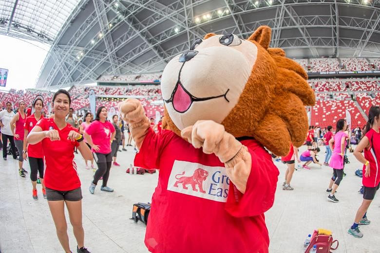 From top: Thousands of Zumba enthusiasts performing dance sequences together at the National Stadium pitch yesterday morning. Great Eastern mascot Sunny and participants of the Great Eastern Women's Run taking part in the Zumba event. They were invit