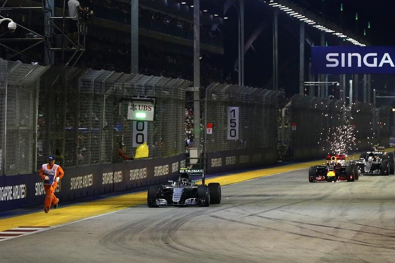 A safety steward running on the side of the track, as the Mercedes of eventual winner Nico Rosberg powers ahead towards Turn 1 at the restart of the race.
