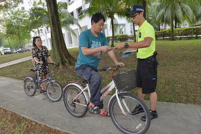 An Active Mobility Enforcement Officer from LTA giving out leaflets to cyclists in Taman Jurong last Wednesday in an exercise to promote the safe sharing of paths and deter reckless behaviour by cyclists and PMD users.