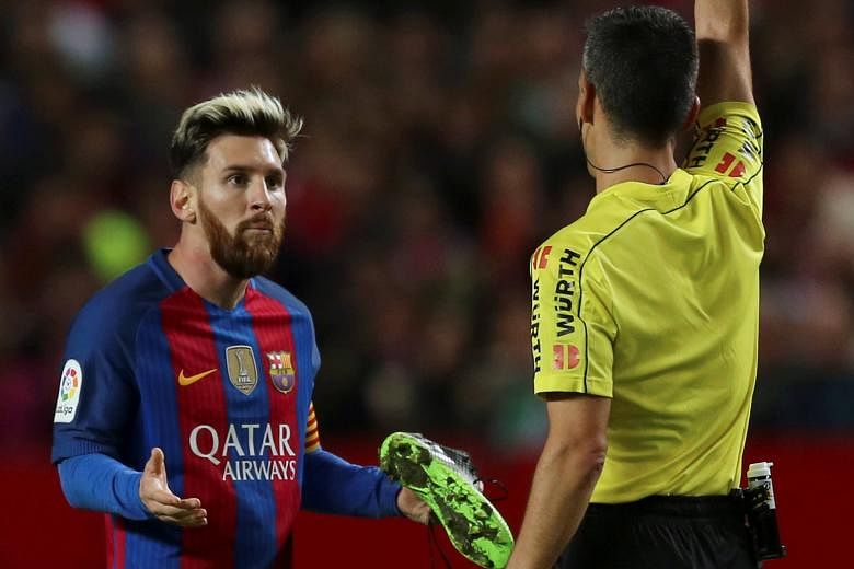 Lionel Messi being booked for time wasting as Barcelona held out for a 2-1 Spanish Primera Liga victory at Sevilla. The Argentinian needed his boots replaced after being tackled, but took his time getting off the ground and was cautioned while headin