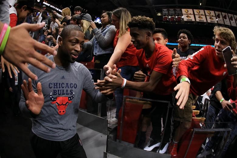 From left: Bulls star Dwyane Wade taking to the court at AmericanAirlines Arena before the game against the Miami Heat. Wade shoots around Heat centre Willie Reed in the first quarter. Wade finished with 13 points, seven rebounds and four assists. Ji