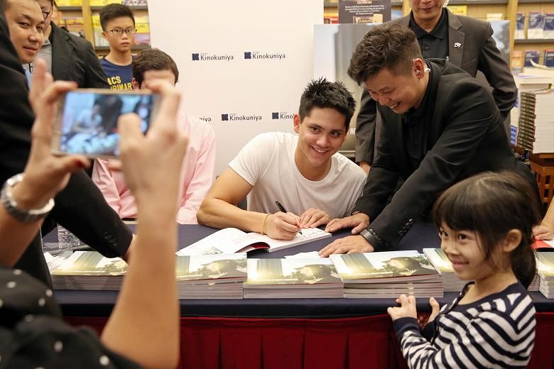 Joseph Schooling signing an autograph for Jenna Wong, seven, at a session for his photo book titled Hello, My Name Is Joseph Schooling at Kinokuniya, Ngee Ann City.
