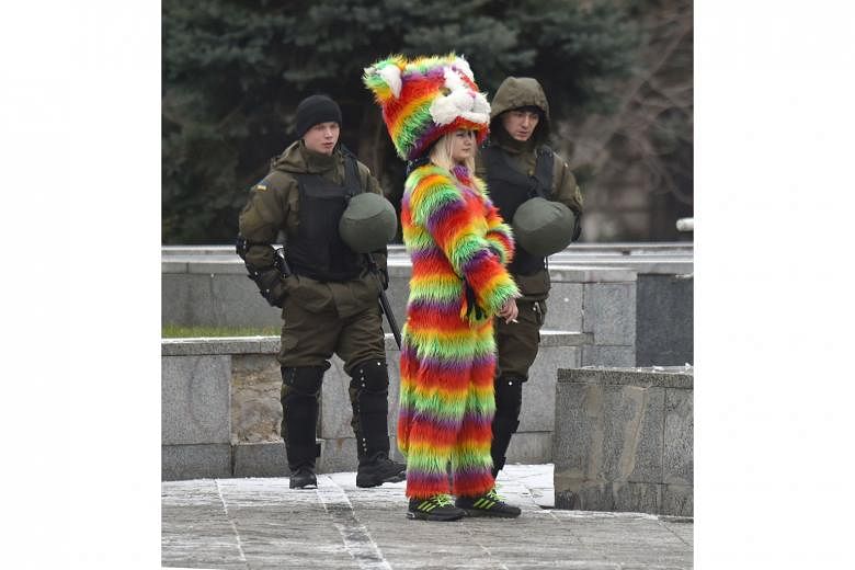 Ukrainian National Guard members walking past a woman wearing a colourful costume as they patrolled near Independence Square in Kiev yesterday, following a night of violence by activists of some far-right Ukrainian parties. Kiev police said they were