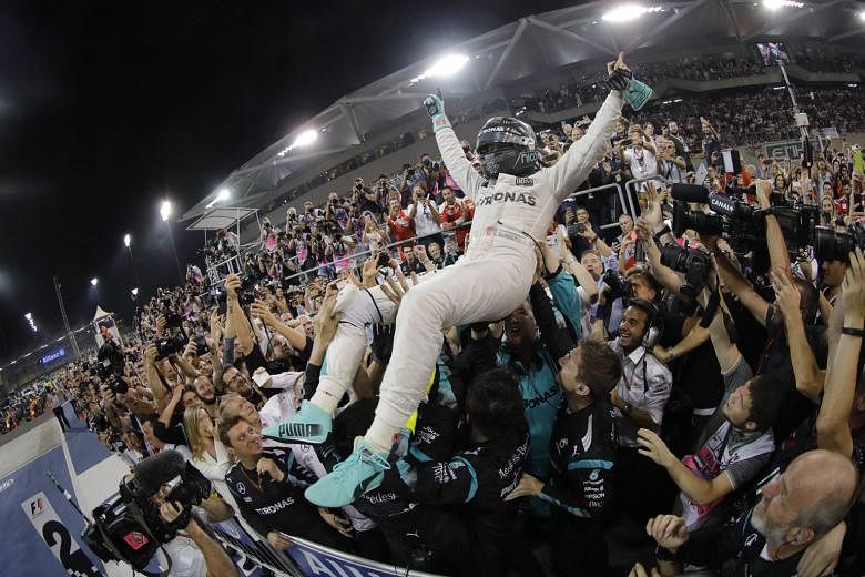 Nico Rosberg celebrating with his team after finishing second in the Abu Dhabi Grand Prix yesterday to win the world title. The German finished the season with 385 points, with Lewis Hamilton on 380.